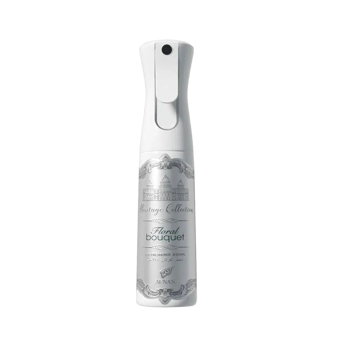 The image showcases a "Floral Bouquet" air freshener spray bottle from the "Heritage Collection" by AFNAN. The design features an elegant white bottle with a grey and white label. At the top of the label, there's an illustration of a classical building, beneath which "Heritage Collection" is scripted in a decorative font. The bottle has a smooth, curved shape with a white nozzle and trigger at the top, and the background of the image is pure white to emphasize the product.