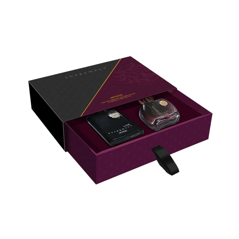 The image depicts a sophisticated perfume gift set by Afnan called "SUPREMACY." The packaging is a rich maroon box with a partial black lid that has the name "SUPREMACY" along with the Afnan logo in gold lettering. Inside the drawer-style box, there is a black leather wallet or card holder with the Afnan logo in silver and a maroon and transparent perfume bottle with a gold emblem. 