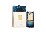 A deep-blue glass perfume bottle with a decorative gold band and a marbled blue-and-gold rectangular cap stands beside a matching white box. The box features a raised pattern, gold accents, and navy-blue marbling at the top, with the product name “Al Nashama” and “Lattafa” printed in gold.