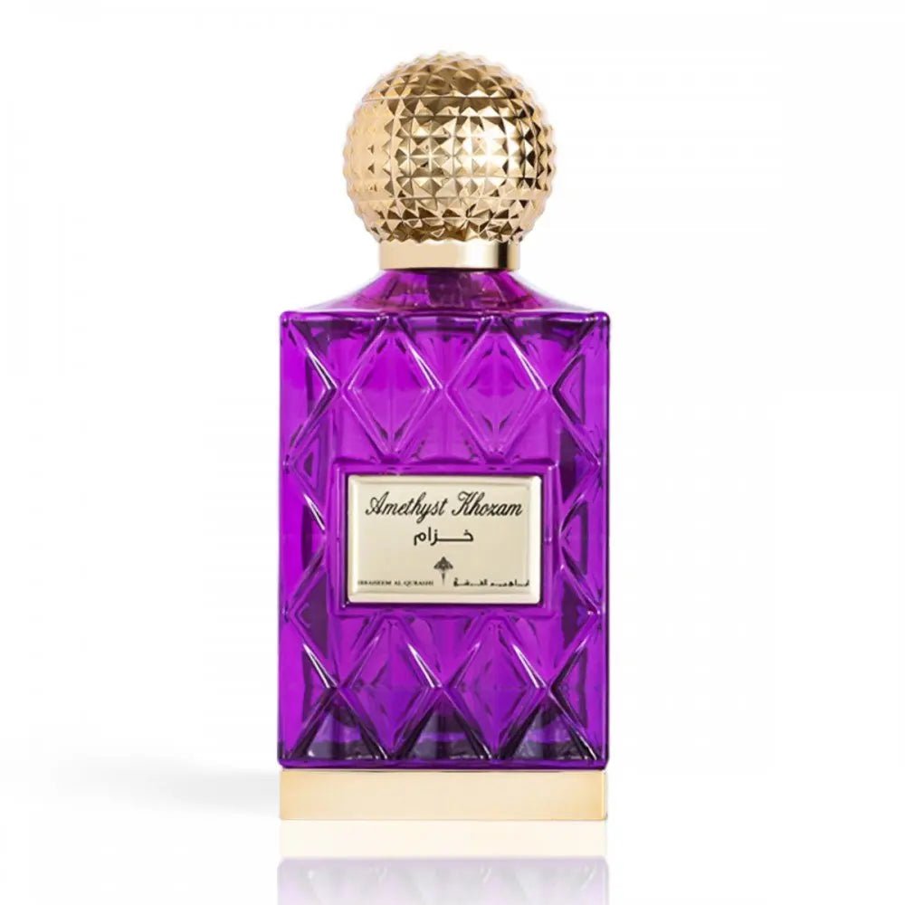 The image shows a luxurious purple glass perfume bottle with a textured gold cap. The label reads "Amethyst Khozam" in elegant script, with Arabic text above and English text below, indicating the fragrance's name by the brand Ibraheem Al Qurashi. The bottle's design has geometric faceted patterns resembling a cut gemstone, and it is positioned against a white background, which highlights the striking purple color and golden details.