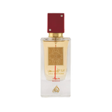 Image of a rectangular clear glass perfume bottle with a red cap embellished with two crystals. The bottle features a gold label with intricate arabesque designs and Arabic calligraphy that reads '??? ????' (Ana Abiyedh), with 'ROUGE' printed in red below. Below the gold label is the brand logo in gold with a flame-like design and the word 'Lattafa'. The perfume liquid appears to be a pale amber color, and the overall design suggests luxury and exotic allure.