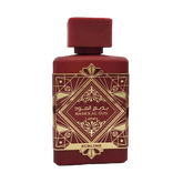 This image shows a deep burgundy perfume bottle with the name "BADEE AL OUD SUBLIME" from the brand Lattafa. The bottle has a matte finish with a matching square cap. It features a luxurious gold geometric pattern with traditional motifs, and the name is written in both Arabic and English. The word "SUBLIME" is displayed on a gold banner at the base. The design conveys a sense of rich heritage and sophistication.