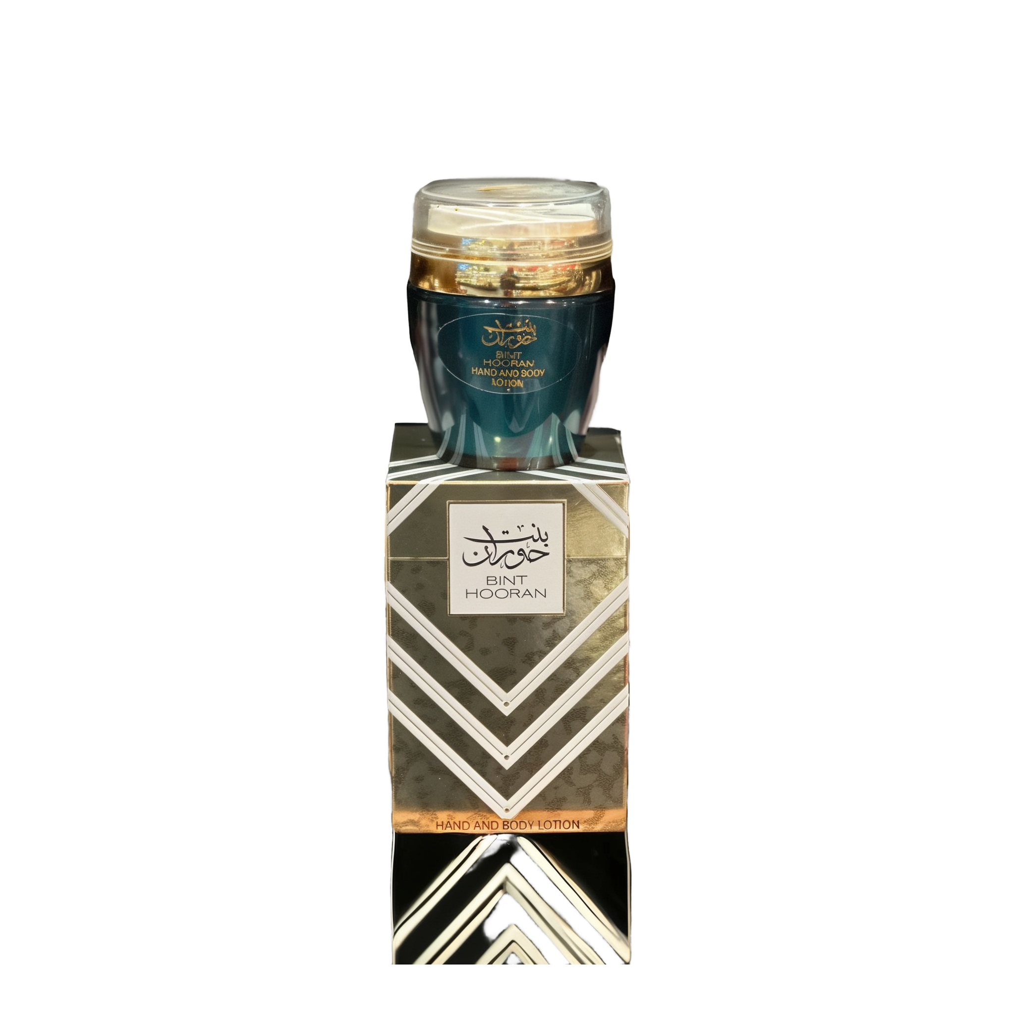 The image shows a product named "Bint Hooran Hand and Body Lotion." The lotion comes in a dark teal container with a clear lid and is placed on top of a matching box adorned with elegant geometric patterns and Arabic calligraphy. The box prominently features the product name "Bint Hooran" along with intricate designs in silver and gold. The luxurious and sophisticated packaging suggests a high-quality skincare product.