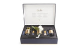 The image showcases an open luxury gift set box from Côte Noire. Inside the navy blue box, various home fragrance products are neatly arranged: two small candles in gold-trimmed glass containers, a reed diffuser, a perfume vial, and an artificial white rose with a gold label, all against a plush black insert. The inside lid of the box features elegant white text detailing the contents and branding.
