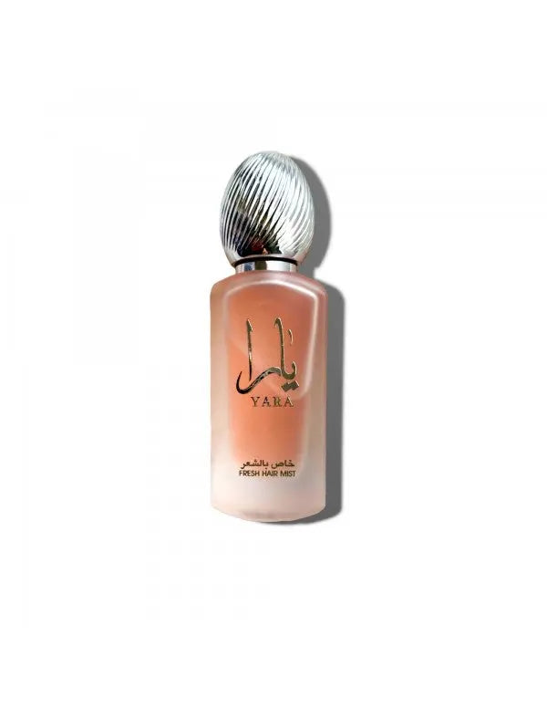 The image shows a frosted glass perfume bottle with a metallic, ribbed cap. The bottle has a soft pink hue and features the label "YARA" in both English and Arabic scripts. Below the brand name, it states "FRESH HAIR MIST" in smaller English lettering, along with Arabic translation. The design of the bottle suggests a delicate and feminine hair fragrance product.