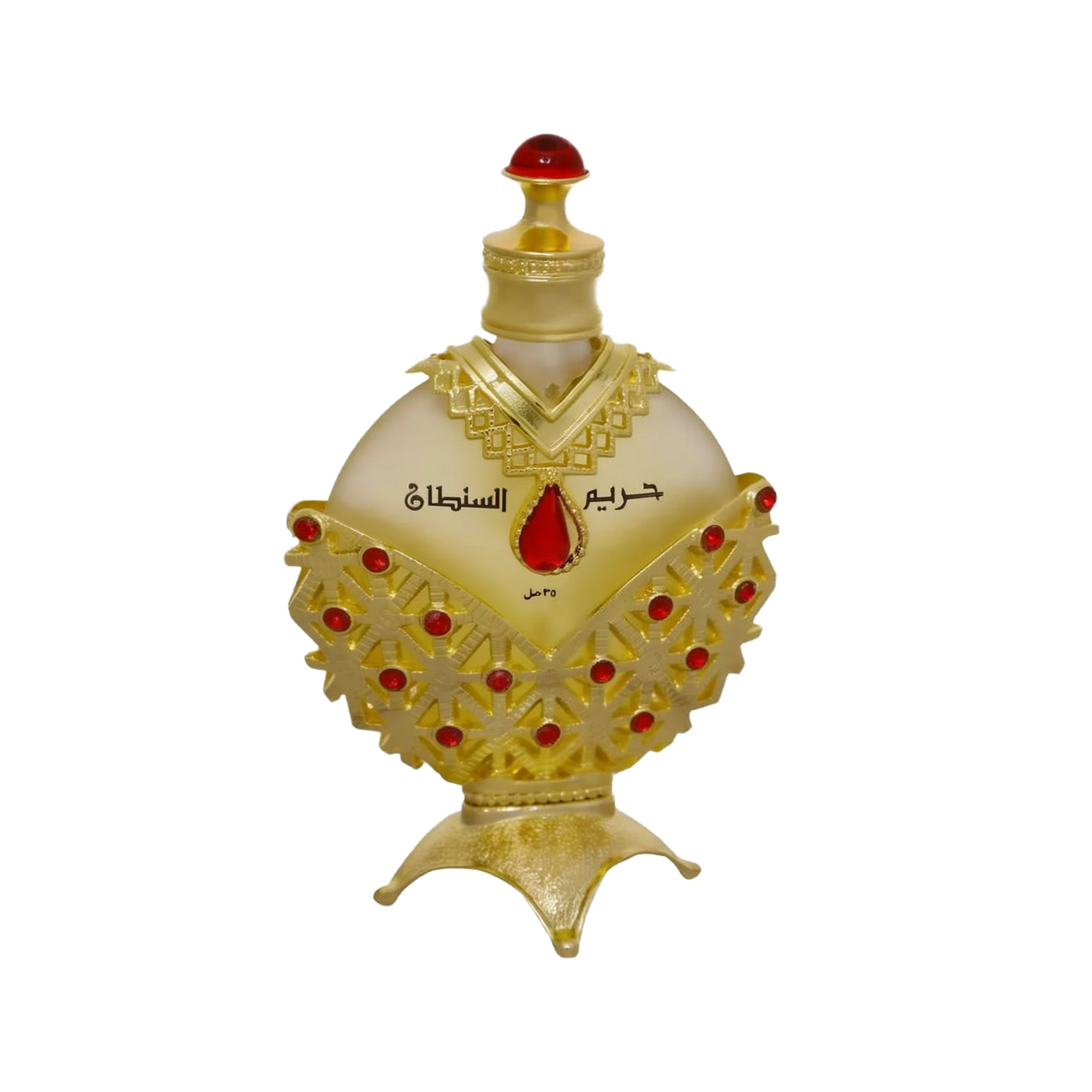 The image displays an opulent perfume bottle with a white background. The body of the bottle is a pale, translucent yellow, topped with a bright red cap resembling a gemstone. The bottle is adorned with a golden overlay featuring intricate cut-out patterns and red gemstone accents. Arabic script is prominently displayed in the center, with smaller text below.