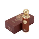 The image features "La Luna" by Gissah, displayed alongside its packaging. The perfume bottle is a sleek copper color with a gold ornate medallion and an intricately designed gold spherical cap. The packaging is a deep brown box with a textured surface and a large gold circular mandala design on the top. The box also has the name "Gissah" and "LA LUNA" along with the description "SIGNATURE COLLECTION LIGHT FRAGRANCE."