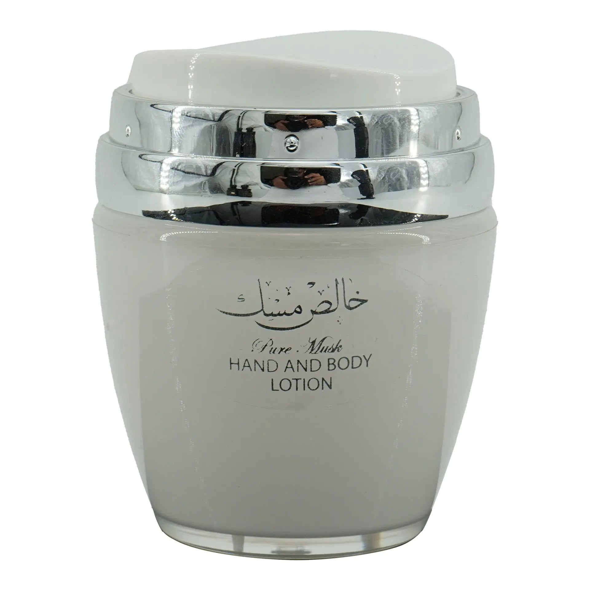 The image features a jar of "Pure Musk" hand and body lotion. The jar is a light gray color with a silver and transparent lid. On the front of the jar, there's a label with Arabic calligraphy at the top and the English words "Pure Musk HAND AND BODY LOTION" printed below. The jar's design is simple yet elegant, with the shiny silver accents of the lid adding a touch of sophistication.