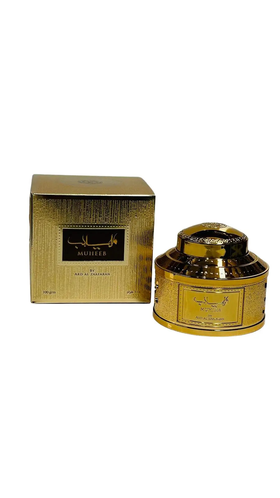 The image shows the Muheeb Bukhoor by Ard Al Zaafaran, which includes a golden textured box and a container. On the left, the square box has a richly textured gold finish with a black label that has the product name "MUHEEB" in white Arabic script and English below it. It states the quantity as "100 grm" and is branded with "BY ARD AL ZAAFARAN." To the right, there is a round golden container with a similar textured pattern and a glossy finish.