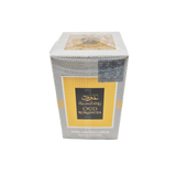 The image features a box of OUD ROMANCEA hand and body lotion. The box has a textured gray pattern resembling reptile skin, with a bold yellow band across the center featuring the product name in both Arabic and English. At the top of the box, there is a transparent section revealing a golden emblem design, while the lower part includes details about the product in smaller text. The overall design of the packaging suggests a luxurious and exotic product.