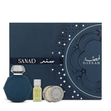 A luxury fragrance gift set featuring a matte navy‑blue octagonal perfume bottle with a silver cap and embossed arabesque pattern, a small clear glass roll‑on vial of pale yellow oil labeled “SANAD,” and a round silver solid‑perfume tin embossed with the Gissah logo. All three items are displayed in front of a matching navy‑blue gift box decorated with subtle geometric textures and printed in white.