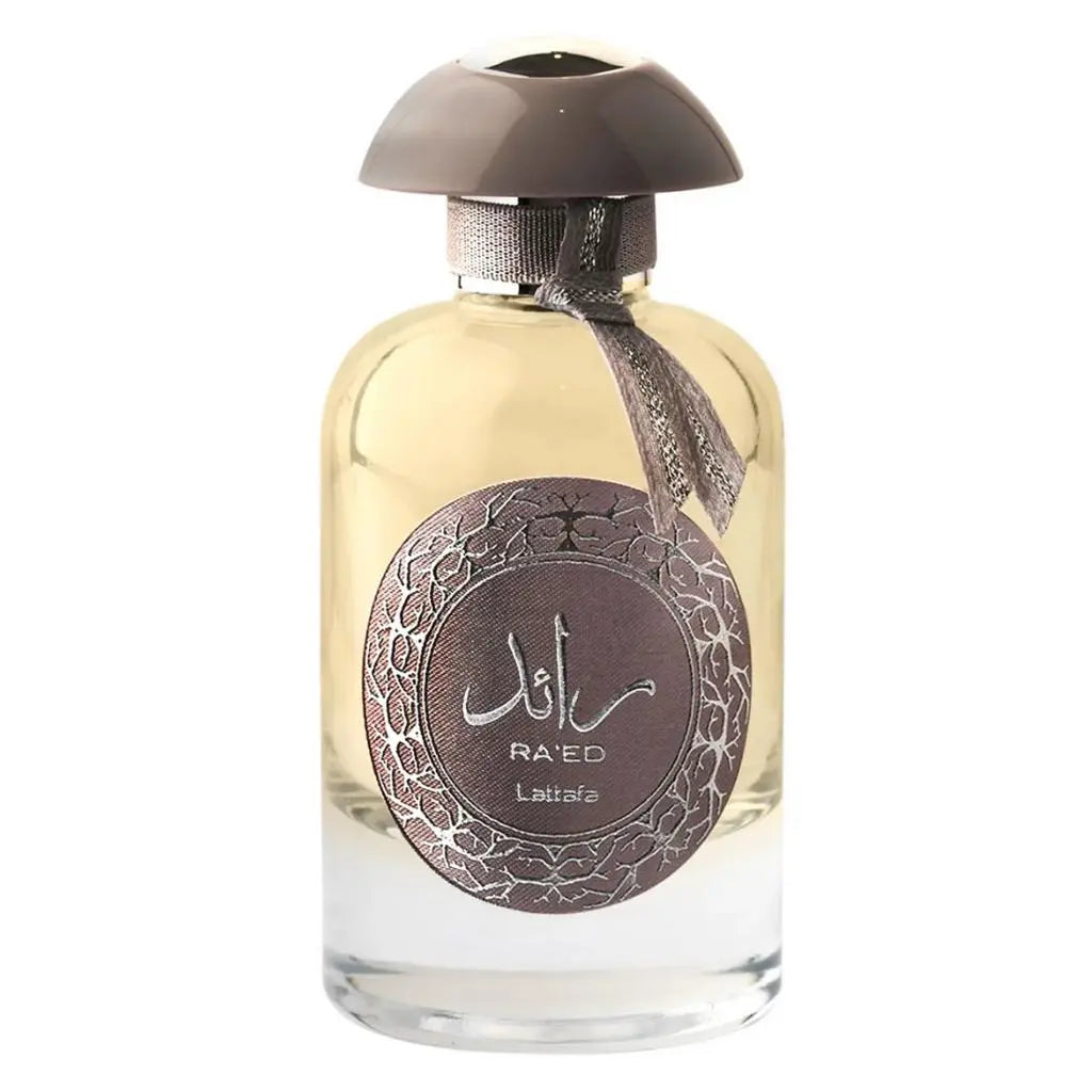 The image is of a perfume bottle. The bottle is transparent with a clear golden-yellow liquid inside, indicative of perfume or cologne. It has a brown cap and a circular label with intricate Arabic calligraphy and English text that reads "RA'ED Lattafa". There is also a brown tassel attached to the neck of the bottle. The background is white, focusing attention on the product.
