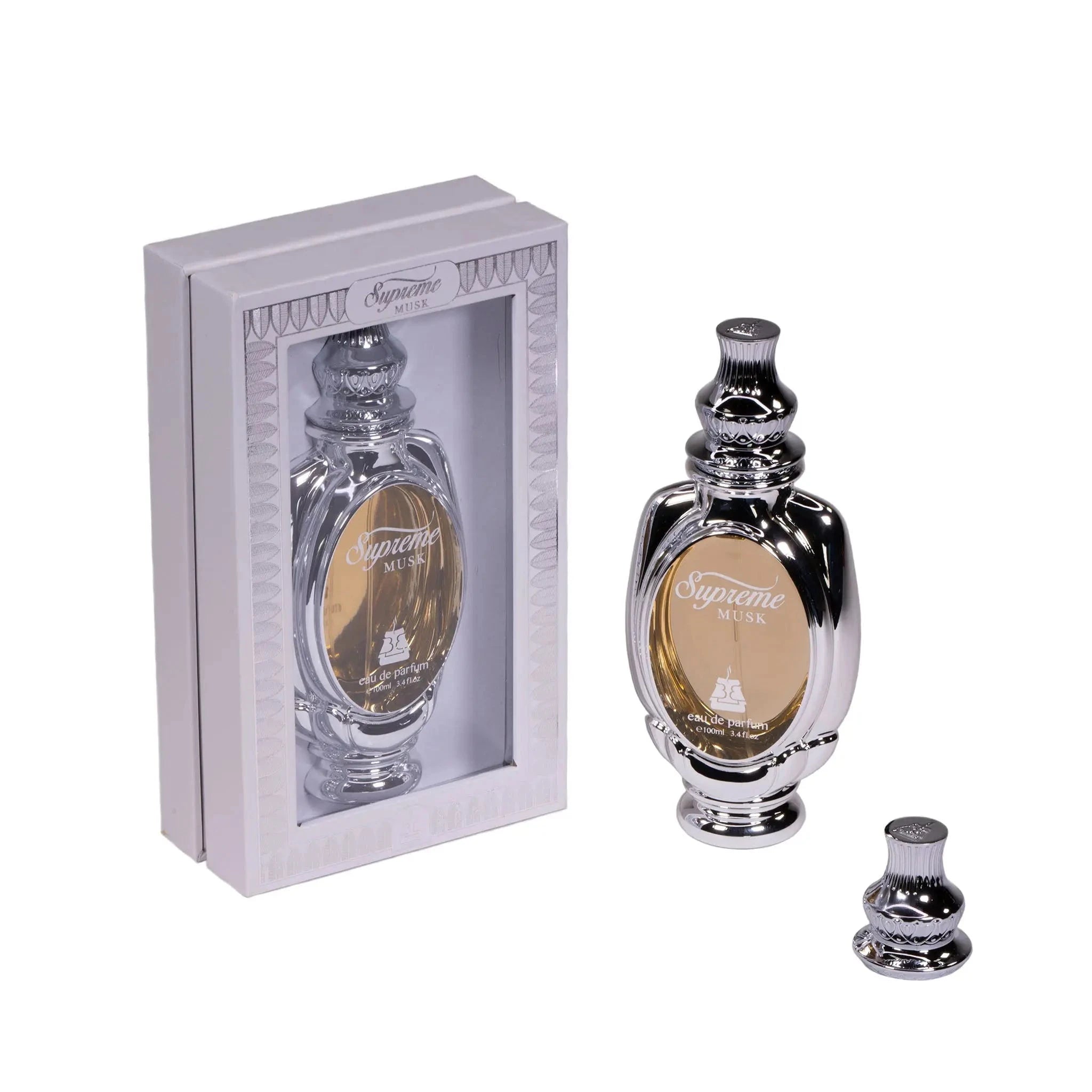 An image of Supreme Musk Eau de Parfum by Bait Al Bakhoor. The product is showcased with the ornate perfume bottle placed in front of its box. The bottle has a shiny black finish with silver accents and a clear central part displaying the golden-colored fragrance within. The bottle's cap is removed and placed in front of it. The box is a light grey color with a framed window that elegantly presents the bottle, and it's adorned with silver ornamental designs at the corners.