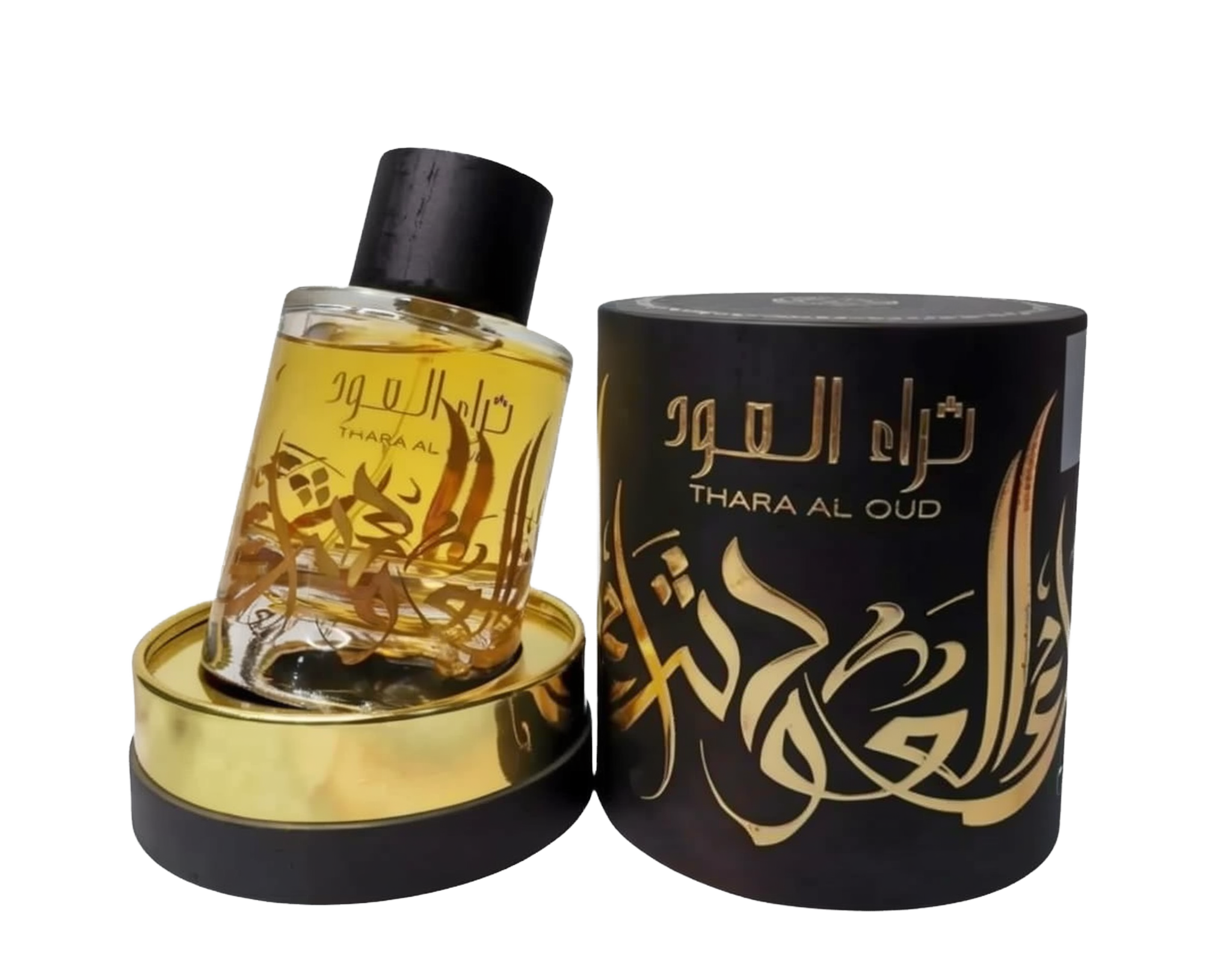 A clear glass perfume bottle with a yellow-amber liquid inside is displayed next to a cylindrical black packaging with gold lettering. The bottle has a dark cap and a gold label with Arabic calligraphy that reads "THARA AL OUD." The packaging repeats the name "THARA AL OUD" in gold Arabic calligraphy and has intricate gold decorative elements. Both the bottle and packaging sit atop a golden base, and the background is neutral, focusing attention on the items.