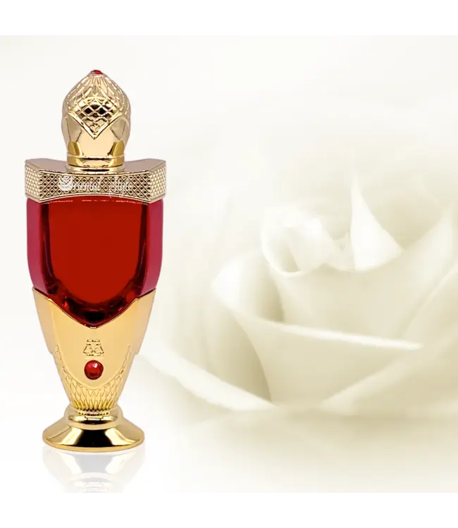 The image features an ornate perfume bottle prominently displayed in the foreground. The bottle has a vivid red center, capped with an elaborate gold lid that has a diamond-like pattern, topped with a decorative finial resembling a gemstone. A matching golden base supports the bottle, with a red gemstone inset just above the base. The background is softly focused, featuring what appears to be a white rose in the right corner, adding a sense of luxury and suggesting the fragrance might have floral notes.