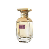 The image shows an elegant perfume bottle with a clear glass body and gold details. The bottle has a hexagonal shape with facets along the base, giving it a jewel-like appearance. The cap is a flat, polished gold with a textured band around the neck featuring a subtle braided design. On the front of the bottle is a rectangular purple label with the words "VIOLET BOUQUET" in white, block letters, and the brand "AFNAN" is printed beneath it. 