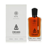 The image features a rectangular glass perfume bottle next to its packaging box. The bottle has a black cap and contains an orange-colored liquid. It has several labels, with "KEHL" at the top, "INTENSE" below it, and a large "DKHAN FRAGRANCES" emblem at the center. The bottle also shows the volume "100 ml", alcohol content "96% vol", and "3.34 fl. oz". There is a small tag on the right side of the bottle. 