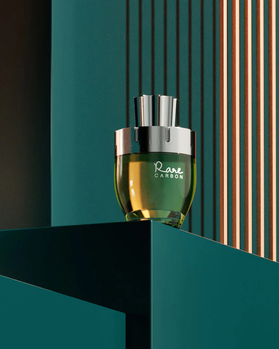 The image shows a bottle of "Rare CARBON" perfume by AFNAN. The bottle has a rounded base with a greenish-yellow tint, which could indicate the color of the perfume, and a metallic silver cap. The bottle's design is modern and elegant, with the name "Rare CARBON" inscribed in white on the glass. It is positioned on a teal-colored ledge against a sophisticated background with vertical copper and teal stripes, providing a rich, contrasting backdrop that complements the bottle's design. 