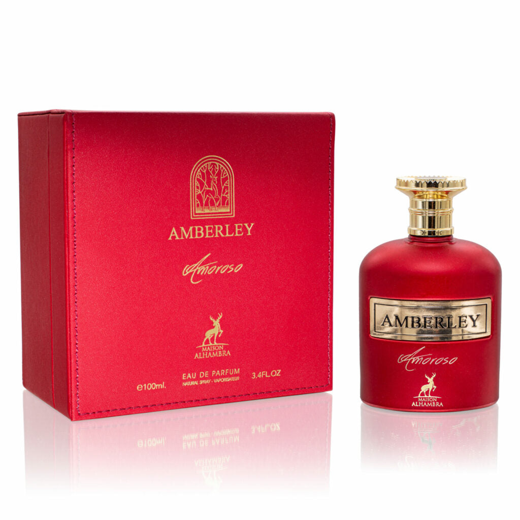 The image shows a red perfume bottle with a textured gold cap alongside its matching red box packaging. The box and bottle are adorned with gold lettering that reads "AMBERLEY amoroso" and feature the emblem of "Maison Alhambra" which includes a stylized tree and a deer. Below the emblem on the box, the text "EAU DE PARFUM 3.4FL.OZ 100ml" is visible. The design is elegant with a reflective surface beneath the items, indicating a luxury fragrance product. 