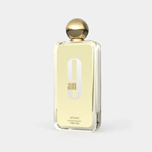 The image shows a rectangular perfume bottle with a gold cap and a clear glass body. It features a prominent "9 am" in stylized font on the front, with the word "AFNAN" written beneath it in smaller, capitalized font. The label indicates that it is an "eau de parfum vaporisateur" and the size is "100ml, 3.4fl.oz." The background is a plain, light color providing a neutral backdrop that accentuates the perfume bottle.