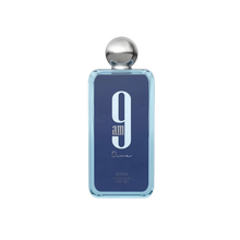 The image shows a rectangular glass perfume bottle with rounded edges. The bottle has a transparent blue tint with a large white number "9" and the text "am" below it in a lighter shade of blue. Beneath this, the word "Dine" is written in a cursive, handwritten style. The cap of the bottle is a polished silver sphere. The brand "AFNAN" is written in small letters at the bottom of the bottle.