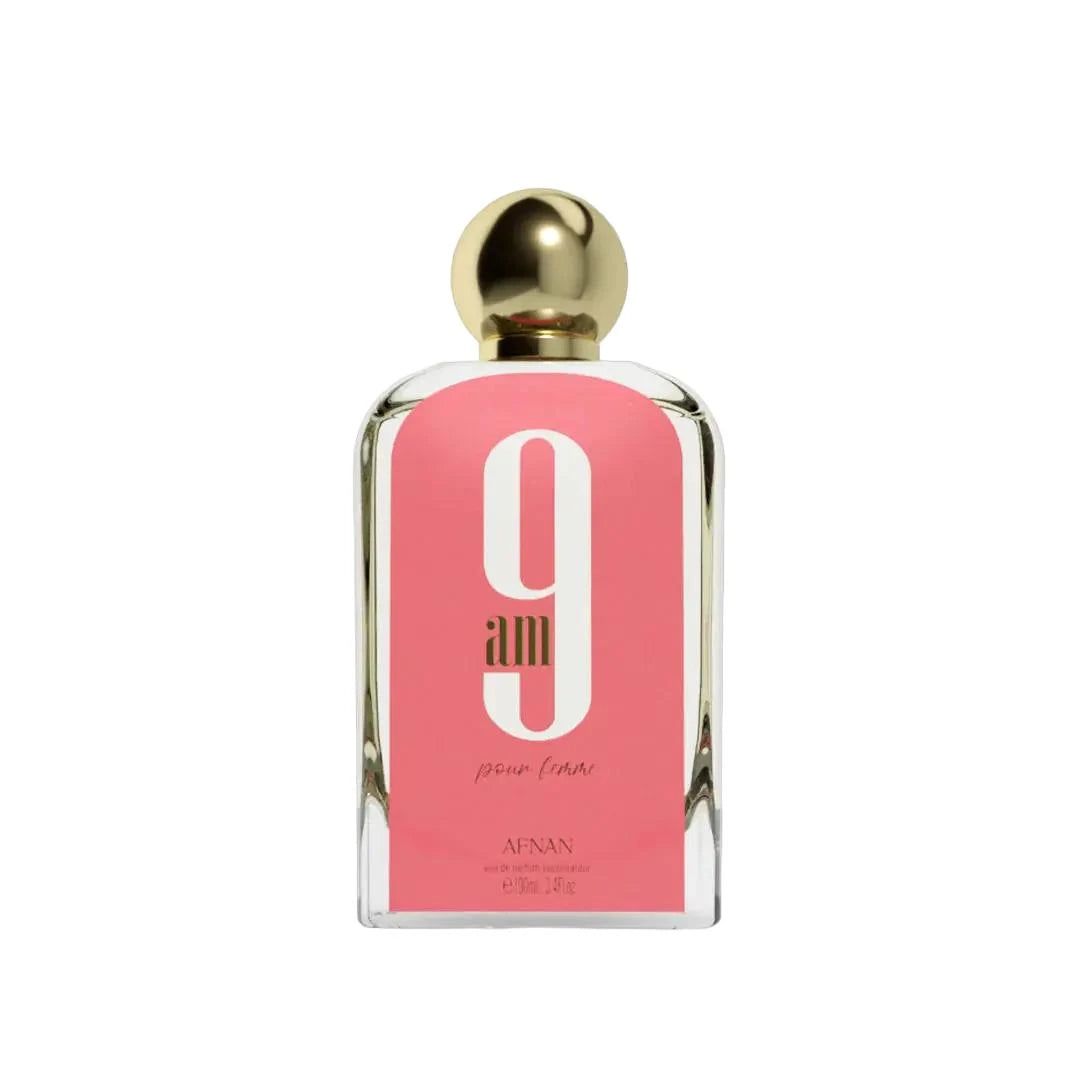 A bottle of "9 AM Pour Femme" perfume by Afnan, featuring a sleek rectangular glass design with a bold pink label, large white number "9", and gold accents including a round, reflective gold cap. The text on the label reads "9 am pour femme" and "Afnan Eau De Parfum Vaporisateur 100ml 3.4 fl.oz".