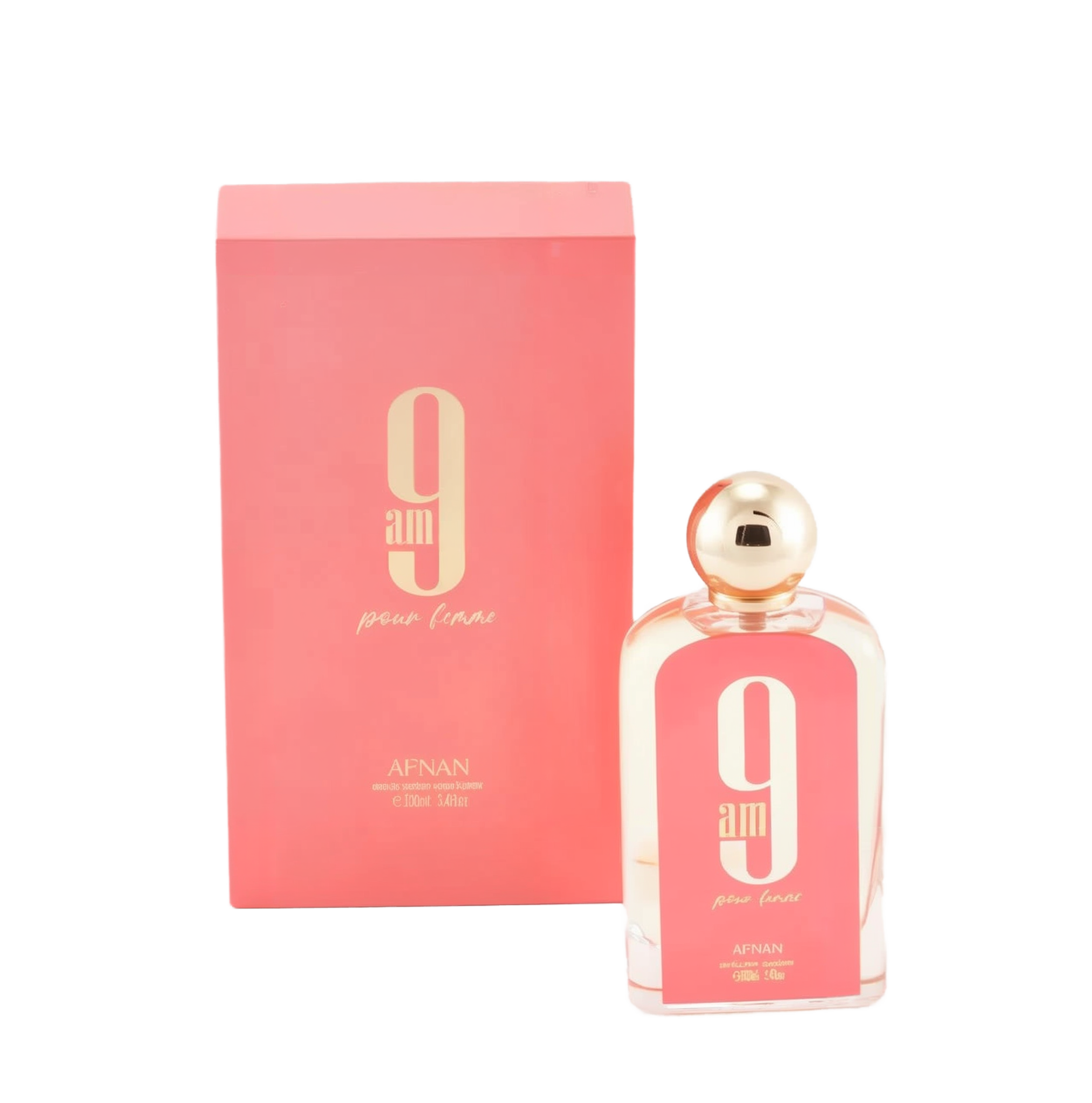 The image displays a rectangular glass perfume bottle and its corresponding box. The bottle is clear with a pink hue and has a white oval label with a large "9" and "am" in black font, with "pour femme" in smaller script below it. The cap is a polished gold sphere. At the bottom of the bottle, "AFNAN" is printed, along with "100ml | 3.4fl.oz". The box is a matching pink color with the same "9 am pour femme" branding and additional text "eau de parfum vaporisateur". 