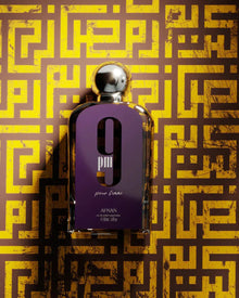The image features a perfume bottle in the foreground with a distinctive purple label and a silver spherical cap. The label has a large white "9" and "pm pour femme" in white lowercase letters, along with the brand name "AFNAN" and the quantity "100ml 3.4fl.oz." at the bottom. The background consists of a complex labyrinth-like golden pattern on a dark base, giving a luxurious and intricate feel to the presentation of the perfume.