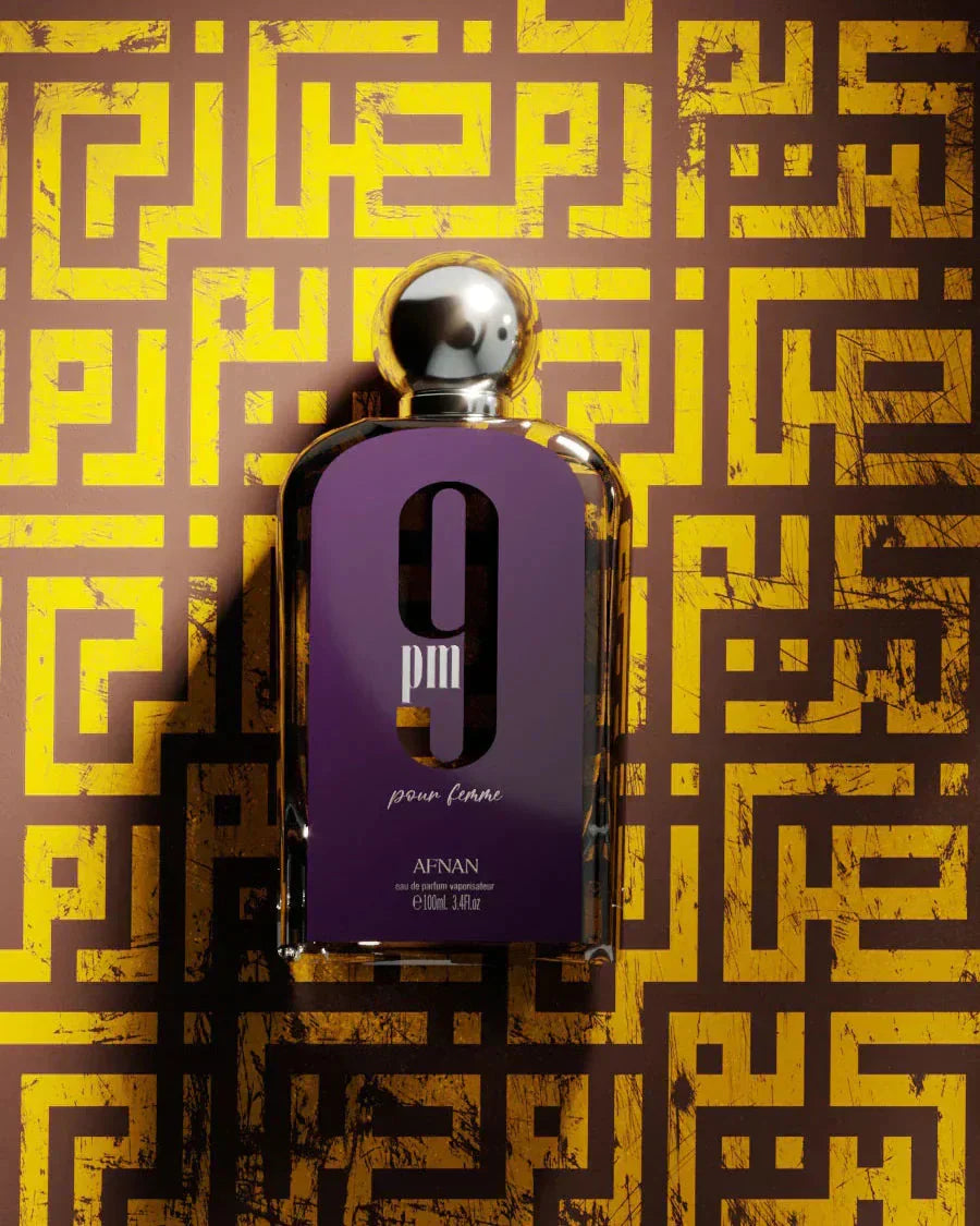 The image features a perfume bottle in the foreground with a distinctive purple label and a silver spherical cap. The label has a large white "9" and "pm pour femme" in white lowercase letters, along with the brand name "AFNAN" and the quantity "100ml 3.4fl.oz." at the bottom. The background consists of a complex labyrinth-like golden pattern on a dark base, giving a luxurious and intricate feel to the presentation of the perfume.