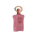 The image features a soft pink perfume bottle with a matte finish and a distinctive design. The bottle has a curved, flask-like shape with a wider base tapering up to a narrow top. A rose gold cap with a circular handle sits atop the bottle, and three small rose gold rings are positioned along the neck. Engraved on the front of the bottle is a heraldic crest-like emblem, with the word "SUPREMACY" arching above it. Below the emblem, the text reads "GOLD AFNAN." 