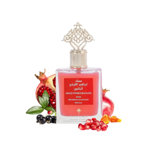 The image shows a product, which is a bottle of perfume named "ABAQ POMEGRANATE MUSK" by Ibraheem Al Qurashi. The perfume bottle has a clear, ornate design with a gold-colored cap featuring intricate patterns. The liquid inside the bottle is a rich red color, and the label is red with white and gold text. Surrounding the bottle are several pomegranates and loose pomegranate seeds, as well as a few black currants, which are likely meant to suggest the fragrance notes of the perfume. 