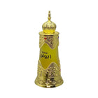 The image shows an ornate golden-yellow perfume bottle with intricate metallic gold details and embossed patterns. The body of the bottle tapers elegantly towards the base and flares out slightly at the shoulder, giving it a regal silhouette. It features Arabic calligraphy in the center, possibly indicating the name of the fragrance or the brand. Adorned with two gemstones, one red and one purple, the bottle has a luxurious and exotic appearance. 