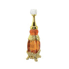 The image shows a luxurious perfume bottle from the brand "Adwaa Al Sharq." The bottle has a tall, elegant design with a combination of amber and gold hues. It features a crystal-like cap, a golden neck, and intricate gold embellishments encrusted with small rhinestones. The base of the bottle is also adorned with ornate gold details, giving it an opulent and sophisticated appearance.