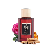 The image depicts a dark red glass perfume bottle with a gold cap, labeled with Arabic calligraphy and English text "Sandalwood" indicating the fragrance. It's from the brand Ibraheem Al Qurashi. The bottle is surrounded by a dark pink rose, some blueberries to the left, and sandalwood sticks in the foreground, suggesting the notes of the fragrance.