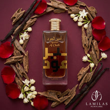 Ameer Al Oudh Intense Oud Lattafa bottle surrounded by oud chips, vanilla beans, jasmine flowers, and red rose petals.