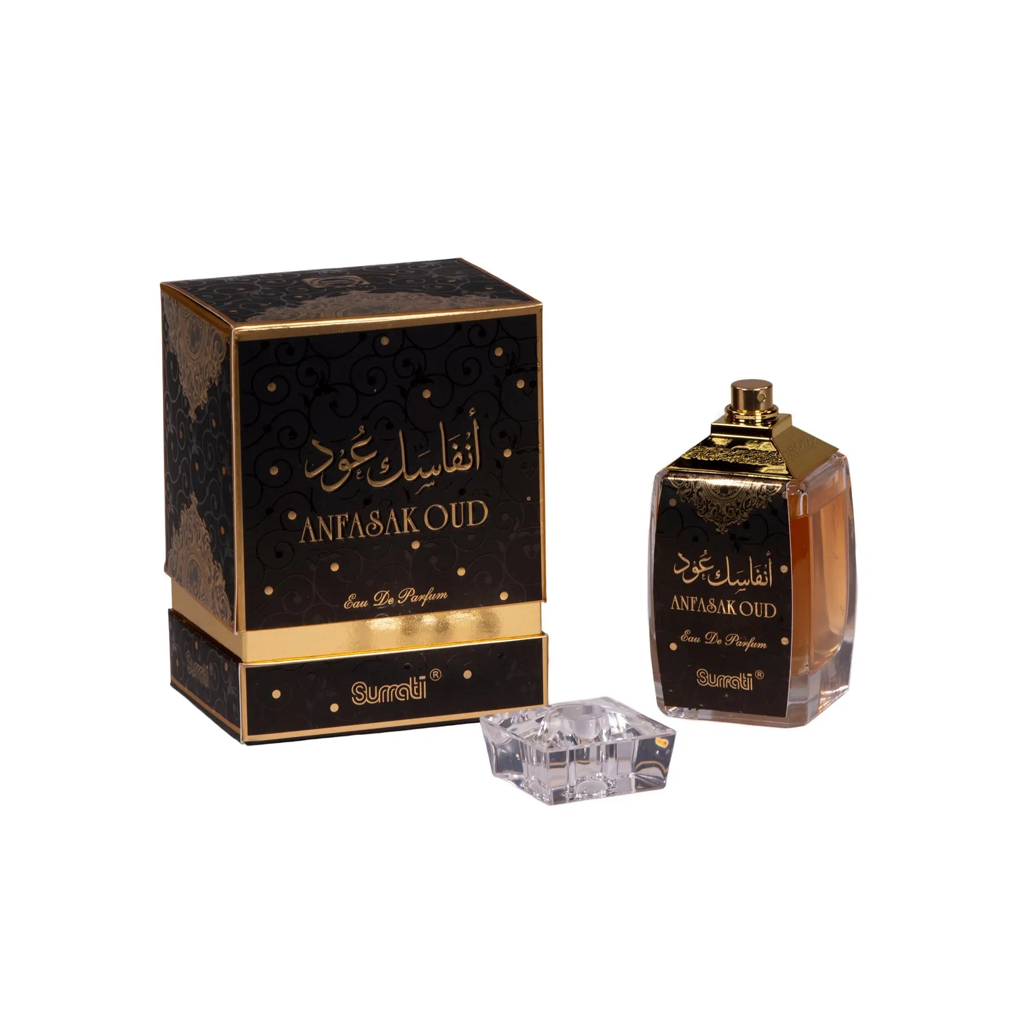 This image displays a perfume bottle with its cap removed, placed beside its packaging box. The box has a black base with an intricate gold paisley and swirl pattern, and it features the name "ANFASAK OUD" in both Arabic and English lettering in gold, indicating a fragrance related to the traditional Oud scent. Below this, also in gold, is the text "Eau De Parfum" and the brand "Surrati." The bottle mirrors the design of the box, with a label that matches the box's pattern and text.