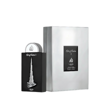 The image shows a perfume bottle and packaging from Lattafa Pride, branded as "Art of Arabia I." The perfume bottle has a sleek black design with a silver depiction of a tall, iconic skyscraper, resembling the Burj Khalifa, embossed on the front. The bott