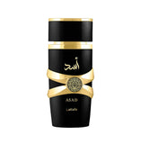 This image shows a sleek, cylindrical perfume bottle named "ASAD" by Lattafa. The bottle is glossy black with a matte black cap. A distinctive gold ribbon-like band wraps around the bottle, holding a circular gold emblem with intricate designs. Below the band, the name "ASAD" is written in gold along with the Lattafa brand name. Arabic calligraphy in gold is featured above the gold band, likely spelling the same name "ASAD."