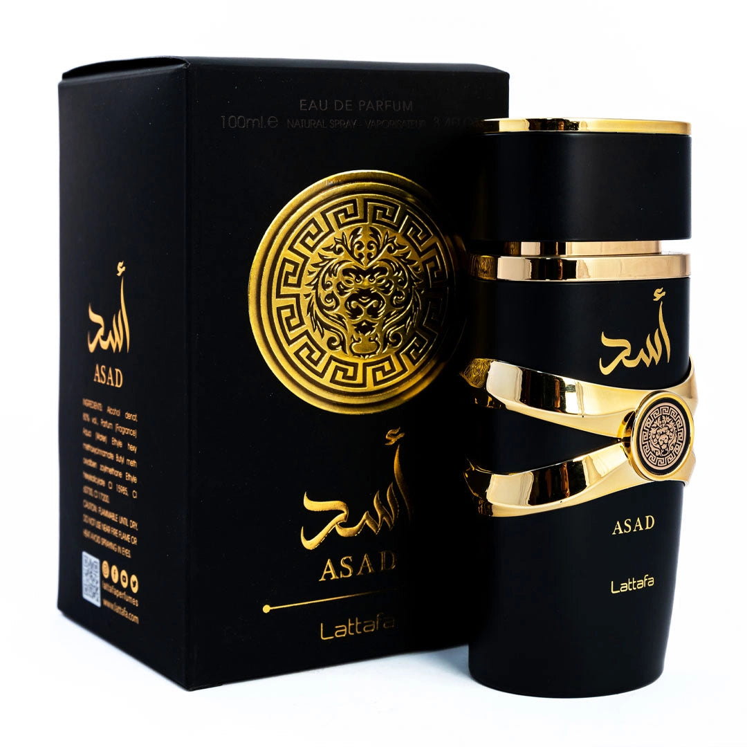 The image features the "ASAD" perfume by Lattafa, positioned beside its packaging. The cylindrical black bottle has gold accents, including a ribbon-like band with a circular emblem and Arabic calligraphy. The name "ASAD" is printed in gold on the bottle and on the matte black packaging. The box also includes details in gold text, such as "EAU DE PARFUM" and the volume "100ml." The design elements are consistent across the bottle and box, suggesting a luxurious and bold fragrance.