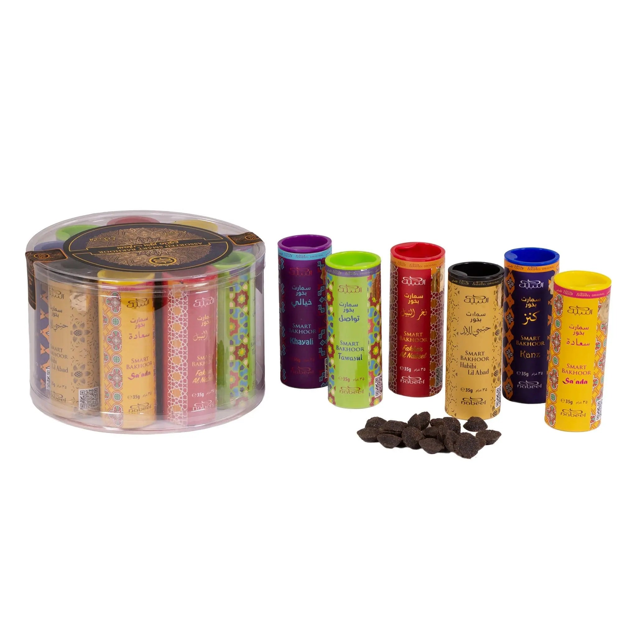 The image features a round, transparent plastic container with a variety of colorful cylindrical bakhoor tubes lined up beside it. Each tube has a different color and is adorned with Arabic calligraphy and English text, possibly indicating different fragrances like "Oud," "Musk," and others. In front of the tubes, there is a small pile of dark brown bakhoor pieces, which are traditionally used for scenting spaces.