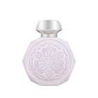 A pale pink, octagonal perfume bottle with intricate, embossed designs on the front. The bottle features a sleek, metallic silver cap that contrasts with the delicate design. The detailed pattern on the bottle adds an elegant and sophisticated touch to its overall appearance.