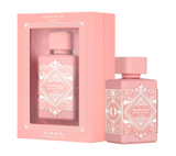 A pink rectangular box with a transparent window, labeled ‘Badee Al Oud Noble Blush’ by Lattafa, displayed next to a matching pink perfume bottle adorned with intricate white geometric patterns and a square cap