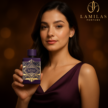 Woman in deep purple dress holding Bade’e Al Oud Amethyst perfume bottle.