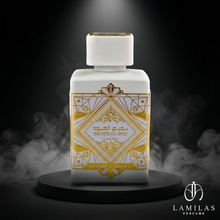 Lattafa Bade'e Al Oud Honor & Glory white perfume bottle featuring a gold Art Deco design, sitting on a black stand in dramatic smoke.