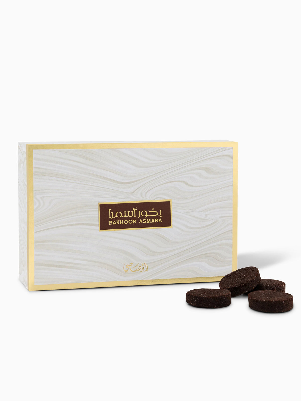 The image shows a package of Bakhoor Asmara by Rasasi Perfumes. It's a rectangular box with a wood grain design in light hues and a golden border. The brand name "Rasasi" and the product name "Bakhoor Asmara" are written in both Arabic and English in a brown rectangle at the center of the box. Below this, there is an ornate golden emblem. In front of the box, there are several dark brown, round bakhoor incense pieces.