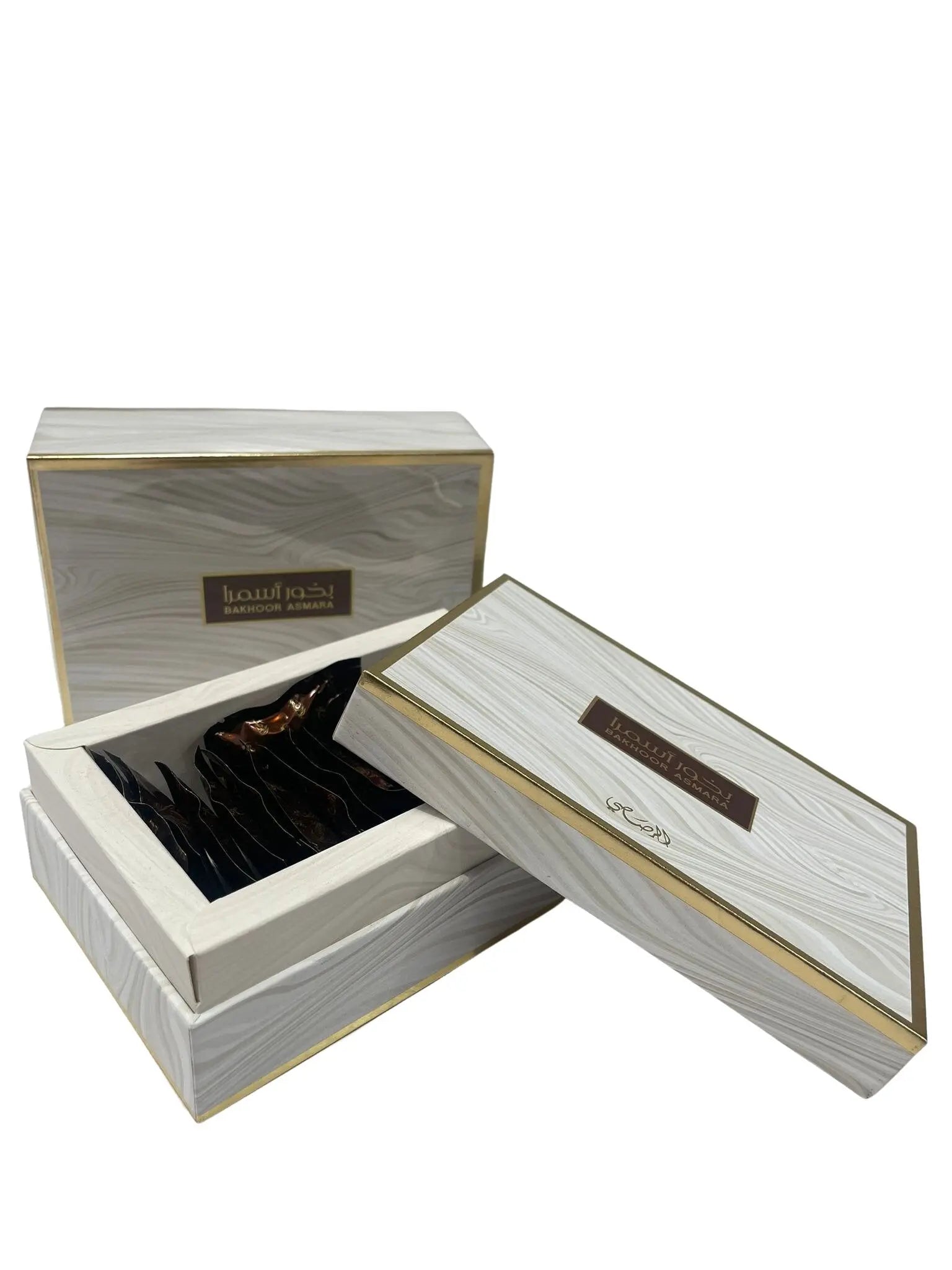 The image features an elegant product packaging for "Bakhoor Asmara". It consists of two rectangular boxes with a wood grain design and golden accents. The larger box is open, revealing a collection of dark-colored incense chips inside. Both boxes have Arabic script and English text on them. The design is sophisticated, with the combination of wood texture print and gold creating a sense of luxury.