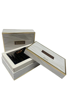 The image features an elegant product packaging for "Bakhoor Asmara". It consists of two rectangular boxes with a wood grain design and golden accents. The larger box is open, revealing a collection of dark-colored incense chips inside. Both boxes have Arabic script and English text on them. The design is sophisticated, with the combination of wood texture print and gold creating a sense of luxury.