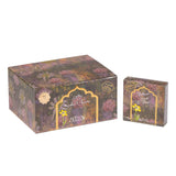 The image shows two boxes of "Bakhoor Jannet El Baqui" from Nabeel Perfumes. The packaging features a floral print with muted tones of purple, pink, and green, giving it a vintage feel. The larger box is cube-shaped, while the smaller one is rectangular, both adorned with a golden ornate label that includes the product's name in Arabic and English script, along with an image of a yellow flower.