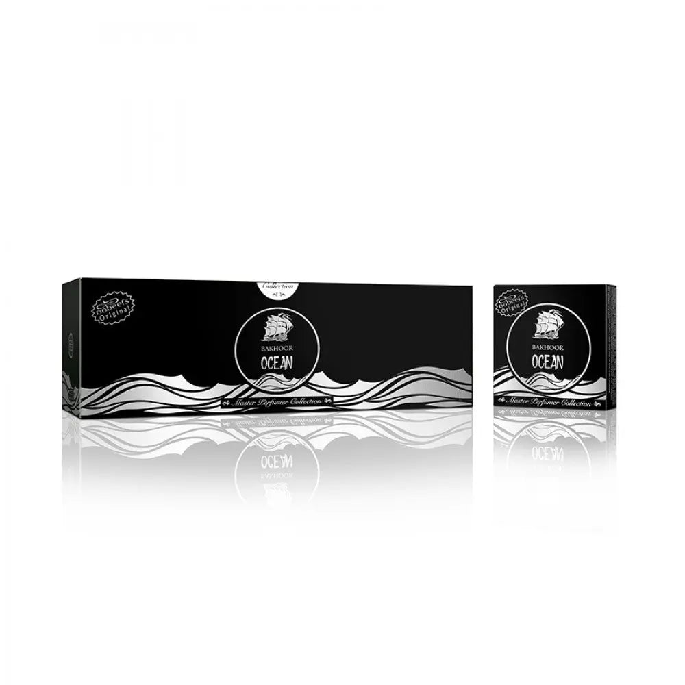The image shows a sophisticated black packaging set for "Bakhoor Ocean" from the Master Perfumer Collection by Nabeel Perfumes. There is a long rectangular box and a matching smaller square box, both adorned with a white and grey wave design along the bottom and a circular white label featuring a sailing ship illustration, indicative of the ocean theme. The name "Bakhoor Ocean" is prominently displayed within the label, with the brand's name at the bottom.