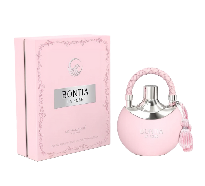 A pale pink, round perfume bottle labeled “Bonita La Rose,” featuring a silver top, braided pink handle, and matching pink tassel, is placed beside a rectangular pink box adorned with subtle scrollwork and a silver logo reading “Bonita La Rose” from “Le Falcone Perfumes.